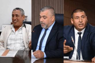 ثلاثة رجال أعمال يتحدثون إلى الميكروفونات ويحملون وثائق