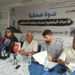 رجلان يتحدثان أمام مجموعة من الميكروفونات على طاولة