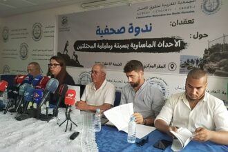 رجلان يتحدثان أمام مجموعة من الميكروفونات على طاولة