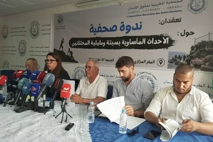 رجلان يتحدثان أمام مجموعة من الميكروفونات على طاولة