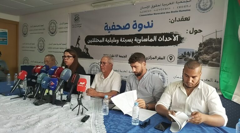 رجلان يتحدثان أمام مجموعة من الميكروفونات على طاولة