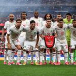 أحد عشر لاعباً من المنتخب المغربي لكرة القدم في الملعب بزي أبيض.