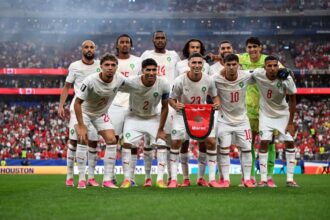 أحد عشر لاعباً من المنتخب المغربي لكرة القدم في الملعب بزي أبيض.