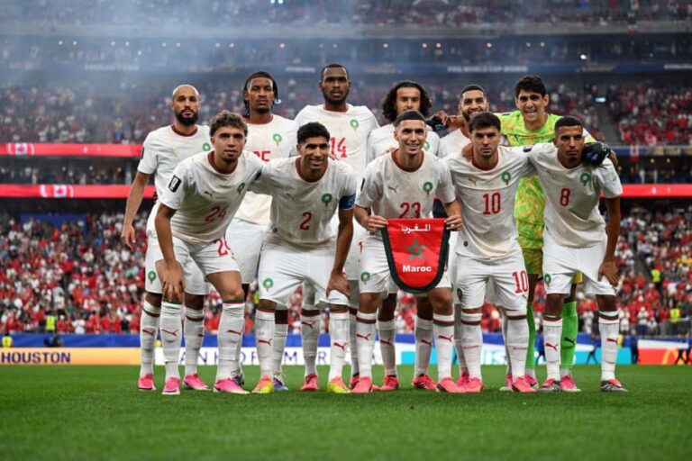 أحد عشر لاعباً من المنتخب المغربي لكرة القدم في الملعب بزي أبيض.