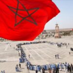 أشخاص يقفون بانتظام أمام مسجد في الصحراء.