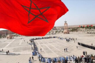 أشخاص يقفون بانتظام أمام مسجد في الصحراء.