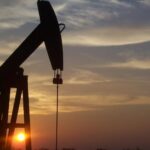 أبراج تكرير النفط تظهر بوضوح في الأفق عند غروب الشمس.