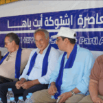 أشخاص يجلسون أمام لافتة زرقاء عليها كتابات