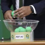 لاعب يسحب قرعة من وعاء زجاجي شفاف.