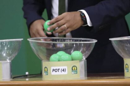 لاعب يسحب قرعة من وعاء زجاجي شفاف.