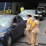 رجال شرطة يرتدون سترات عاكسة يتحدثون مع ركاب سيارة متوقفة.