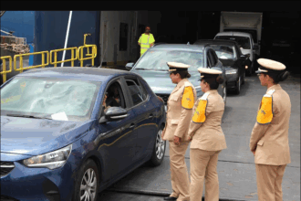 رجال شرطة يرتدون سترات عاكسة يتحدثون مع ركاب سيارة متوقفة.