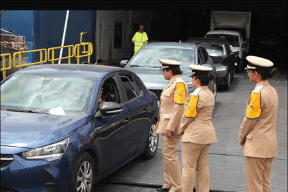 رجال شرطة يرتدون سترات عاكسة يتحدثون مع ركاب سيارة متوقفة.