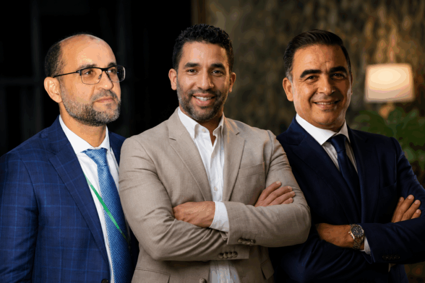 ثلاثة رجال يرتدون قمصاناً بيضاء، يتحدثون في مكان مغلق.