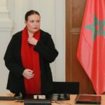 امرأة ترتدي وشاحًا أحمر وتعدل قميصها.