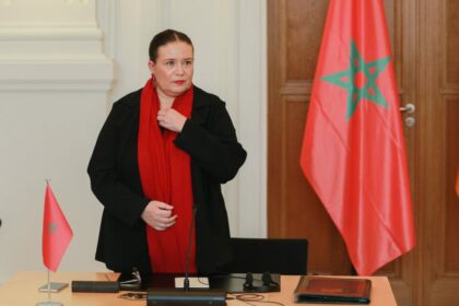 امرأة ترتدي وشاحًا أحمر وتعدل قميصها.