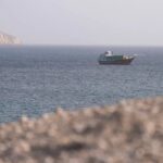 قارب صغير يبحر بالقرب من جزيرة في مضيق هرمز