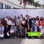 مجموعة من الأشخاص يقفون بجانب لافتة بيضاء.