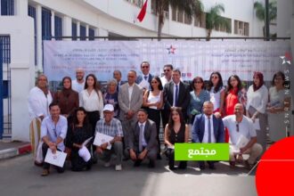 مجموعة من الأشخاص يقفون بجانب لافتة بيضاء.