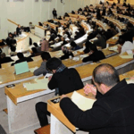 طلاب يجرون امتحانات في قاعة دراسية.