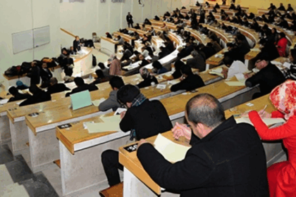 طلاب يجرون امتحانات في قاعة دراسية.