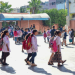 تلاميذ يرتدون وزرات بيضاء وزرقاء في ساحة مدرسة