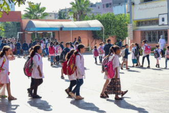 تلاميذ يرتدون وزرات بيضاء وزرقاء في ساحة مدرسة