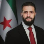 صورة جانبية لرجل بجانب علم سوري.