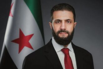 صورة جانبية لرجل بجانب علم سوري.