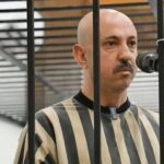 رجل أصلع يتحدث في الهاتف عبر بوابة سجن مقلمة