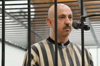 رجل أصلع يتحدث في الهاتف عبر بوابة سجن مقلمة