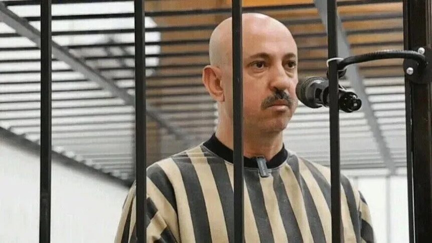 رجل أصلع يتحدث في الهاتف عبر بوابة سجن مقلمة