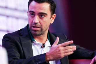 تشافي هيرنانديز يجلس على كرسي وذراعه مرفوعة