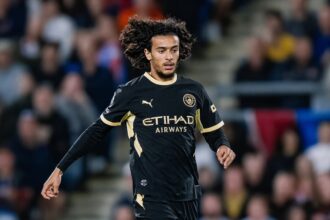 لاعب كرة قدم يرتدي قميص مانشستر سيتي ويحمل شعار الاتحاد