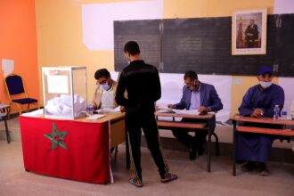 شخص يتحدث أمام مجموعة من الأشخاص الجالسين في قاعة
