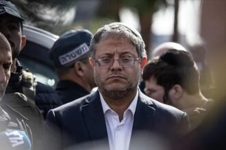 إيتمار بن غفير يرتدي قبعة ويشاهد شيئاً خارج الإطار