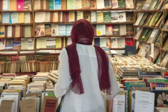 شخص يتفحص رفوف الكتب في معرض