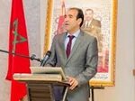 رجل يرتدي بدلة يلقي خطابًا بجوار علم المغرب