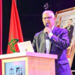 نزار بركة يتحدث من على منصة وخلفه علم المغرب.