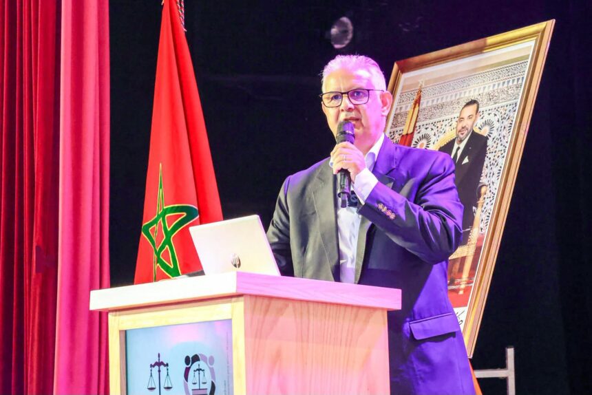 نزار بركة يتحدث من على منصة وخلفه علم المغرب.