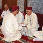 رجال بلباس تقليدي أبيض يجلسون ويؤدون مهامهم.