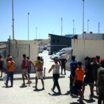 أشخاص يسيرون عند مدخل مبنى، يرتدون معدات السلامة.