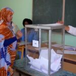ثلاثة رجال يوقعون على وثائق، وامرأتان تحملان لوحات مفاتيح.