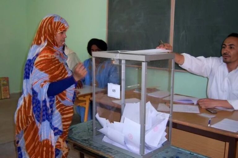 ثلاثة رجال يوقعون على وثائق، وامرأتان تحملان لوحات مفاتيح.